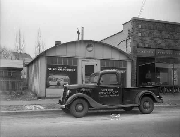 Welch Oyl-Ayr Heating Co., 1437 Regent Street, (Trachte building) with Ford truck parked in front. The building is next to M.J. Nilles Sheet Metal and Furnace Shop, 1439 Regent Street.