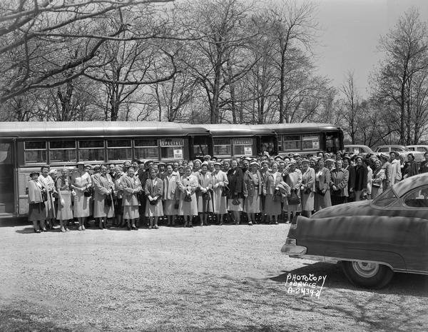 Large group of Knights of Columbus women, standing in front of buses made to look like railroad cars, returning from a convention held in Racine.