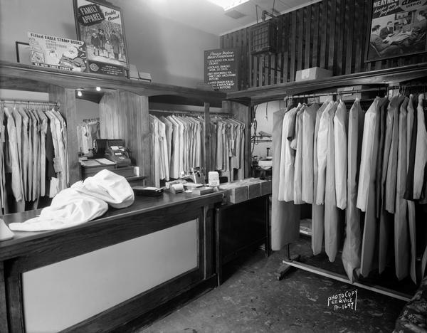 Interior of Four Lakes Cleaners, showing counter where clothes are dropped off and picked up, and cleaned clothes hanging on racks. 612 S. Park Street.