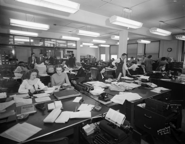 Large office room with men and women working at desks at CUNA (Credit Union National Association), 1342 East Washington Avenue.