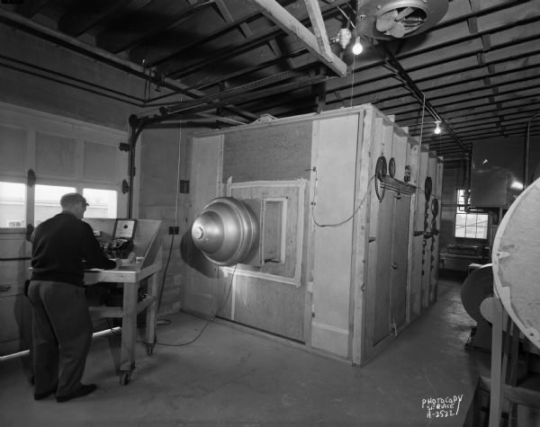 Man operating a ventilator testing cabinet at W.R. Carnes Company.