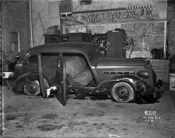 Close-up of wrecked Packard sedan in garage.