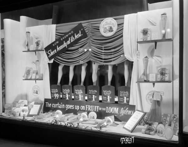 Hill's Department Store, 202 State Street, display window featuring Fruit of the Loom woman's nylon stockings and signs stating: "Sheer Beauty at its Best," and "The Curtain Goes Up on Fruit of the Loom Nylons."