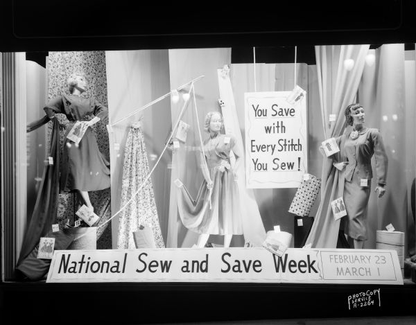 Hill's Department Store, 202 State Street, sewing display window including three female mannequins, fabric, dress patterns, and two signs stating "You Save with Every Stitch you Sew," and "National Sew and Save Week."