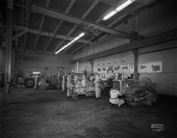 Nagle-Hart Tractor Company, 212 South Thornton Avenue, interior view showing repair department with men working on Caterpillar and Case equipment.