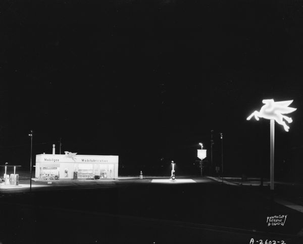 Night view of Robert Blossom's Mobil gas station, 3702 East Washington Avenue and Highway 51. Includes the Mobil red horse sign on a pole.