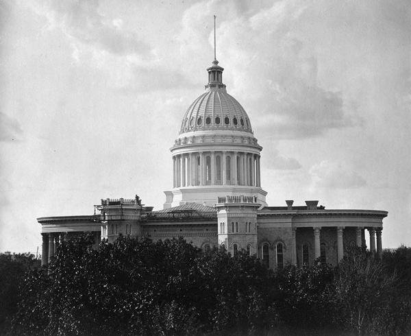 The Wisconsin State Capitol as it appeared after the completion of the dome in 1869. At that time only the dome and the upper stories can be seen above the trees in the Capitol Park.