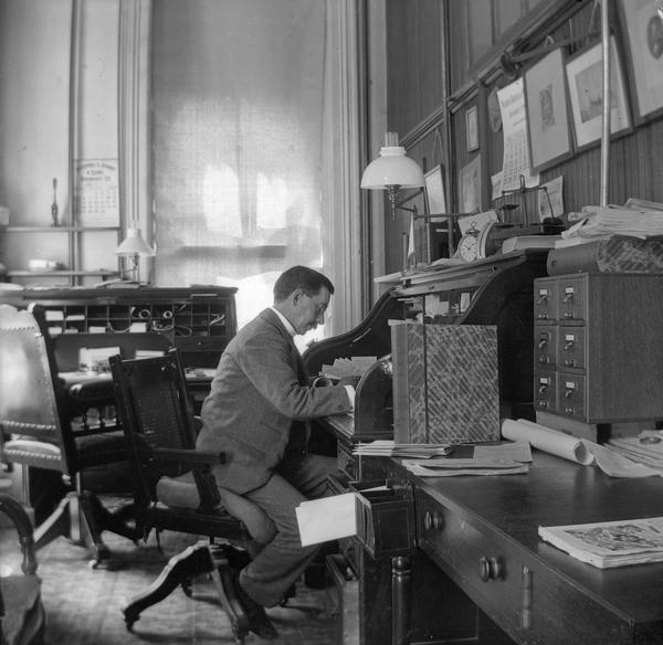 Reuben Gold Thwaites, secretary of the State Historical Society, at his desk in the South Wing of the third Wisconsin State Capitol. Thwaites succeeded Lyman Draper as head of the Society in 1887, and it was Thwaites who was responsible for many of the progressive practices that made the Historical Society a national leader in its field.  This portrait embodies Thwaites' reputation as a dynamic administrator and a tireless historian. It also permits us an excellent view of the Eastlake swivel chairs in his office.    
