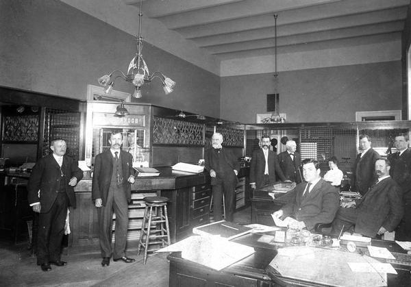 Staff of the State Treasurer at work. Although the office was clearly located in the third Wisconsin State Capitol, this photograph may have been taken after the Capitol fire of 1904, because the men's clothing suggests a later date. This is possible because the North Wing of the Capitol was not damaged by the fire. It continued to be used until 1913 when it was destroyed to make way for the new Capitol.