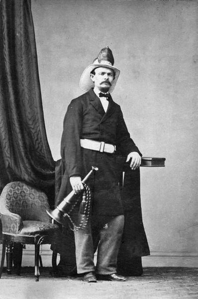 William Thomas Fish, who served as Madison's fire chief, 1867-1868.  Although posed for a formal studio portrait, Fish is wearing his uniform and hat and holding a fire trumpet.