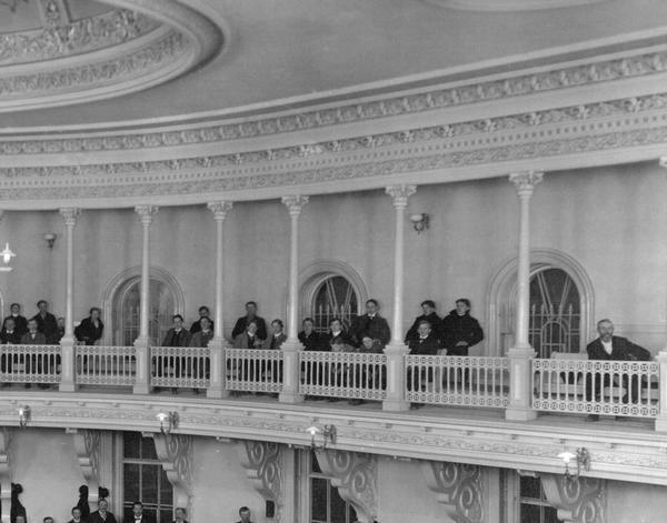 Detail of the Assembly Chamber photograph, showing the visitors' gallery, the oversize brackets that supported it, and the ornamentation of the gallery. As originally decorated in 1869 the iron brackets are known to have been painted to resemble wood; the metal columns were faux marble, with their iron caps painted white and gilded. The space between the ornamentation of the cornice and the ceiling centerpiece was light blue and the chamber walls were stippled in violet. Overall, a more colorful appearance than could be expected from the black and white image.