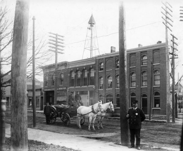 Station #2 of the Madison Fire Department at 125 State Street. Several men in uniform pose in front of the building with a horse-drawn wagon. A sign on the left side of the building reads: "Embalmers and Fun[era]l Directors."