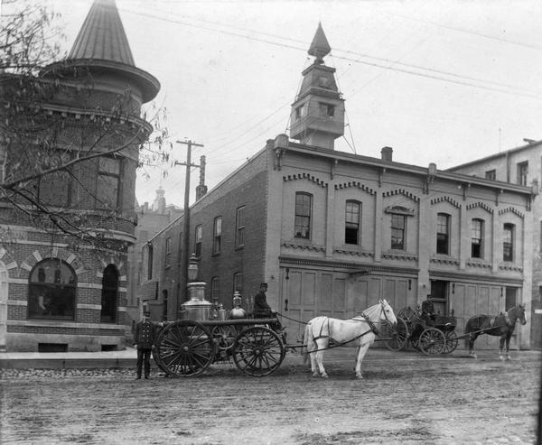 Madison's old Central Fire Station (1881-1904), 10 South Webster Street, with Police Station on the left. Probably photographed at the turn of the century by William G. Barckhan. In the immediate foreground is a steam fire engine; behind it is a hose wagon. This building was originally the Billings Plow Works and then became the Police Garage, and later Littel Printing Co. after the fire department moved out.