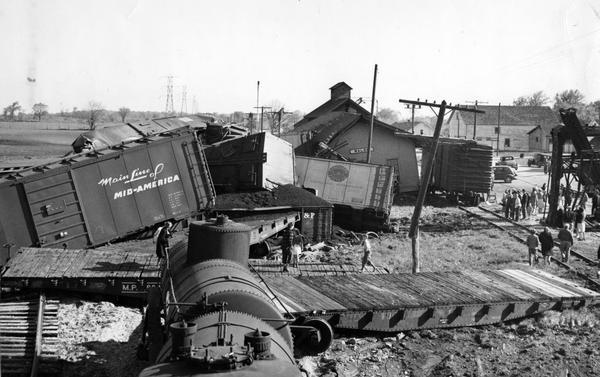 Elevated view of wreck of a Chicago, Milwaukee and St. Paul Railroad freight train. The derailment is so severe that the train station has been knocked off its foundation.