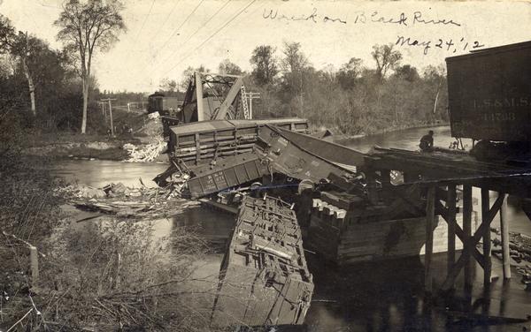 Wreck of a Minneapolis, St. Paul & Sault St. Marie Railroad train on a bridge over the Black River near Withee. The damage is so severe that the cars have fallen into the river and the bridge is nearly destroyed.
