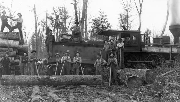 A logging crew of the Upham Lumber Company, together with the company's locomotive, "Old Vanderbilt," formerly the Wisconsin Central Railroad's Engine No #47, bought in 1880 from the New York, Providence and Boston Railroad where she was named "Oregon." The locomotive was built by the Taunton Locomotive Works in 1847 and later rebuilt and renamed, the "C. Vanderbilt" in 1860. The engine was sold by the Wisconsin central in 1887 to the Upham Lumber Company. No. 47 was inside connected, had power cranks on the main driving axle, a copper fire box, and was a wood burner. Shown here are engineer Frank Leuckenbach and his crew of lumberjacks. 