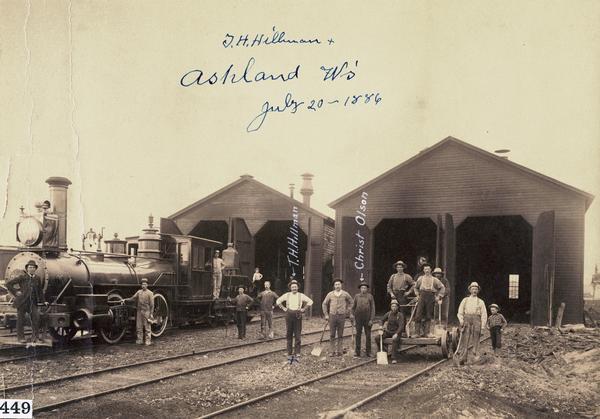 Group of people posing in the rail yard of the Chicago, St. Paul, Minneapolis, & Omaha Railway.