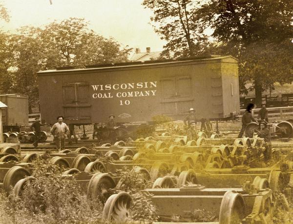Group of men transferring bodies of a standard gauge box car (of the Wisconsin Coal Co.) to the narrow gauge tracks of the Fond du Lac, Amboy & Peoria Railway at Iron Mountain, Wisconsin.