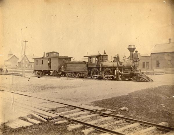 A Chicago, St. Paul, Minneapolis & Omaha Railroad engine pulling a pay car. Identified employees include: (left to right) brakeman E.W. Sweet and fireman Callen on the running board. The original print is from the collection of railroad historian Carl R. Gray, whose papers are available at the Historical Society Archives.