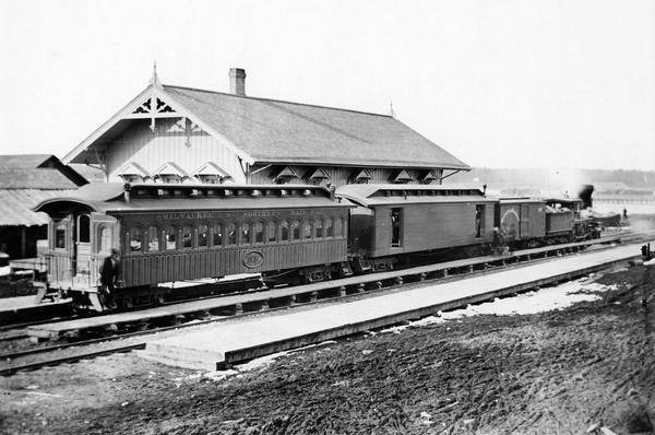 At the De Pere depot, the first train operated by the Milwaukee & Northern Railway. This train made its first run to Green Bay on June 25, 1873, and this photograph may well have been taken later that same year. In 1884 the Milwaukee & Northern was incorporated into the Chicago, Milwaukee & St. Paul Railway. It is thought that the engine may be the "Cedarburg," built for the Wisconsin Central in 1871.