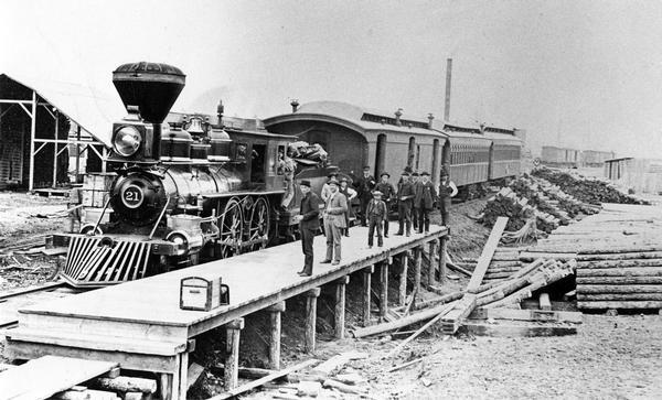 Elevated view of the first passenger train to arrive at Merrill, a Chicago, Milwaukee & St. Paul Railway train. The passengers are waiting on a platform and there is no depot.