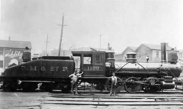 Chicago, Milwaukee and St. Paul railroad locomotive #1100, a class I engine, built by the Baldwin Locomotive Works in 1873 and originally numbered #199. The locomotive was renumbered #100 in 1898 and #1100 in 1899, and eventually scrapped in 1917. The engine is shown here at the foot of the Eighth Street, Fowler Street Yard. The engineer is James McCauley, and the fireman is William Connett.
