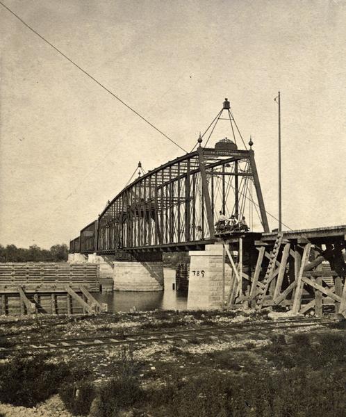 Construction of a railroad bridge on the Chicago, Milwaukee, and St. Paul Railroad line. A set of railroad tracks is in the foreground, running along the shoreline.