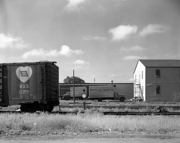 View across railroad tracks of warehouses on the northern outskirts of Menasha which are leased by the Kimberly-Clark Paper Company. Trucks are parked alongside the railroad tracks.