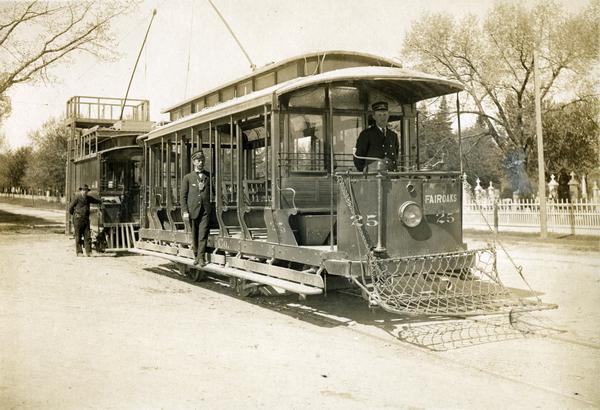 An open streetcar labeled Fair Oaks sitting near Forest Hills Cemetery, which was then the end of the line. The motorman has been identified as Jack Schwenn and the conductor is Charlie Cramer. The third man is unidentified.