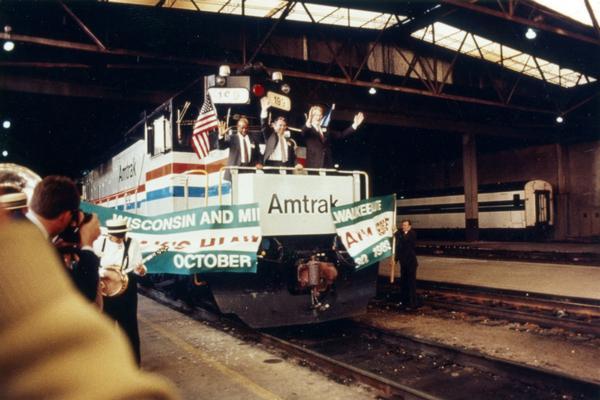 Wisconsin Governor Tommy G. Thompson, a member of the Amtrak governing board, joins an unidentified Amtrak official as the train breaks a ceremonial banner at the Amtrak station marking the start of increased service on the famous Hiawatha line between Chicago and Milwaukee. The new service was subsidized in part by Wisconsin and Illinois.