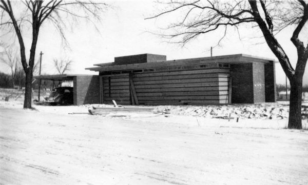 Front elevation of the Herbert Jacobs Residence known as Jacobs I, designed by Frank Lloyd Wright, during construction. A car is parked in the carport.