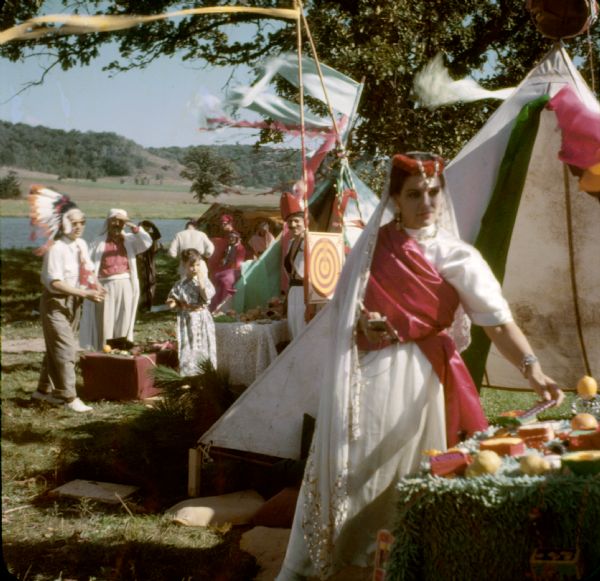 Tents, people in costume, and food tables at a carnival on the grounds of Taliesin. Taliesin was the Wisconsin residence of Frank Lloyd Wright and the Taliesin Fellowship. Taliesin is located in the vicinity of Spring Green, Wisconsin.