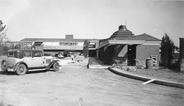 Cars in the driveway in front of the Herbert F. Johnson Residence, "Wingspread," during construction. The residence was designed by Frank Lloyd Wright and completed in 1937.