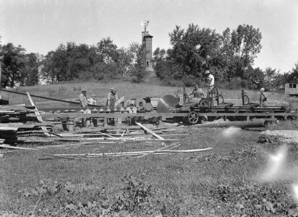 Workers working on the construction of the drafting studio at the Taliesin Fellowship Complex used by the Taliesin Fellowship. The Romeo and Juliet windmill is in the background. Both structures were designed by Frank Lloyd Wright. Taliesin is located in the vicinity of Spring Green, Wisconsin.