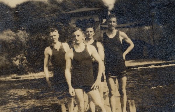 Theta Chi fraternity members standing on the pier in front of the Lake Mendota Boathouse located at the foot of North Carroll Street. The boathouse was designed by Frank Lloyd Wright. The fraternity members are, left to right: Ronald Mattox (class of 1922); Willard Valentine "Shorty" Erdman (class of 1921); unidentified fraternity member; and Merwin Hayden Howes, Jr. (class of 1923). Mattox kept a canoe in this boathouse for several years.
