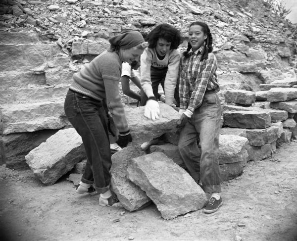 Three female members of the First Unitarian Society helping to stack stones during the construction of the Frank Lloyd Wright-designed Meeting House. Members of the congregation helped to transport the stone from a quarry north of the Wisconsin River to the building site.