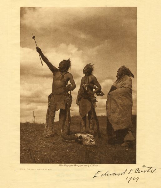 Three Crow Indians with Buffalo skull at their feet take an oath. Signed by Curtis, 1909.