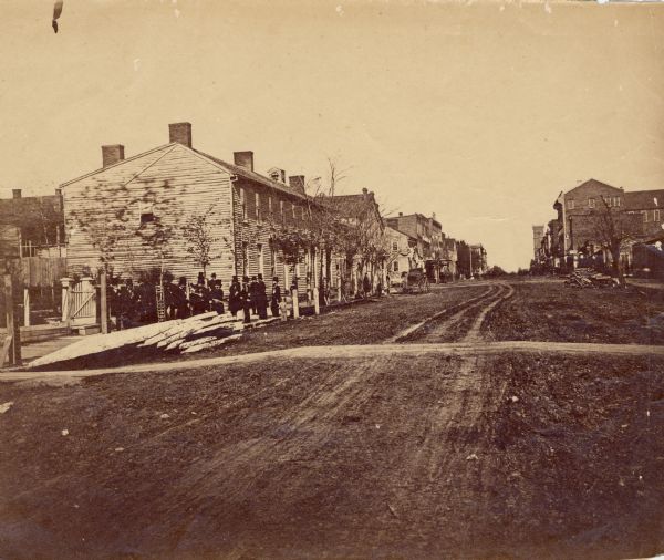 Albumen print of the Globe Tavern during Abraham Lincoln's funeral.  The tavern was the early home of the Lincoln family. A group of dignitaries are standing near the building.