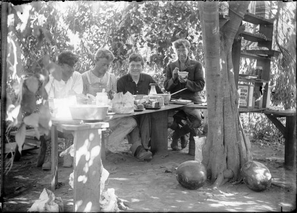 Arnold Gesell and friends at breakfast in California during the time they built a rustic cottage called "Casa Verduga." Box of Corn Flakes is visible at right.