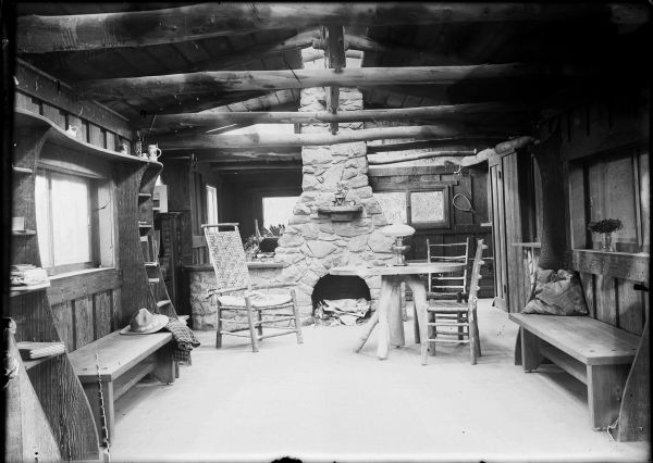 Interior of cabin with fireplace at one end of a long room.