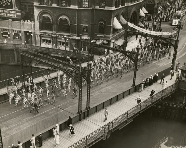 Elevated view. As part of Boy Scout Day at the Wisconsin State Fair, a contingent of scout flag bearers marches over the Wisconsin Avenue Bridge over the Milwaukee River.