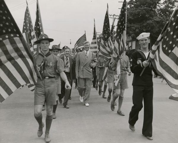 Escorted by an honor guard of scouts, Mayor Carl Zeidler leaves City Hall to dine at the Dairy Lunch at the State Fair. As always, Zeidler is impeccably dressed. He is also escorted by Russell Frost, chair of the Wisconsin Junior Fair.
