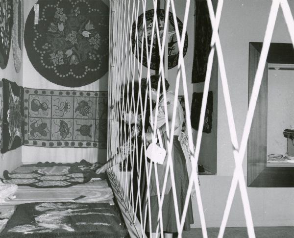 A visitor to the Wisconsin State Fair is so curious about one entry in a display of rugs and textiles that she reaches through a protective barrier in order to more closely examine it.