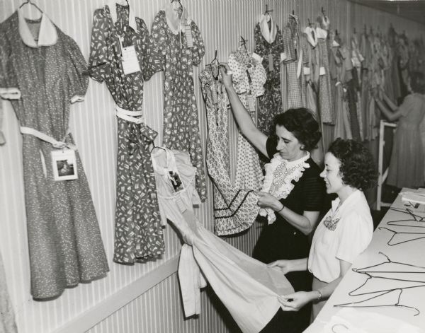Clothing judges Helen Pearson from Madison and Mrs. Hugh Cunningham from Milwaukee examine dresses entered in the home sewing competition at the Wisconsin State Fair.