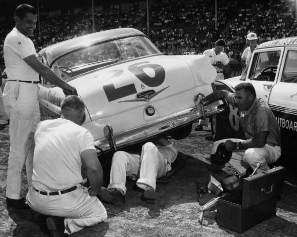 The pit crew works on #26, a Ford Fairlane, during an automobile race at the Wisconsin State Fairgrounds.