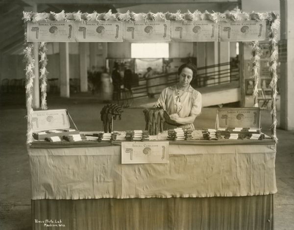 Exhibit of Ideal Curlers at the Wisconsin State Fair, with a woman demonstrating how they were to be used for long hair. The advertising promises "no metal to cut or injure the hair."