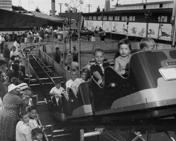 Young children ride a small roller coaster at the Wisconsin State Fair.