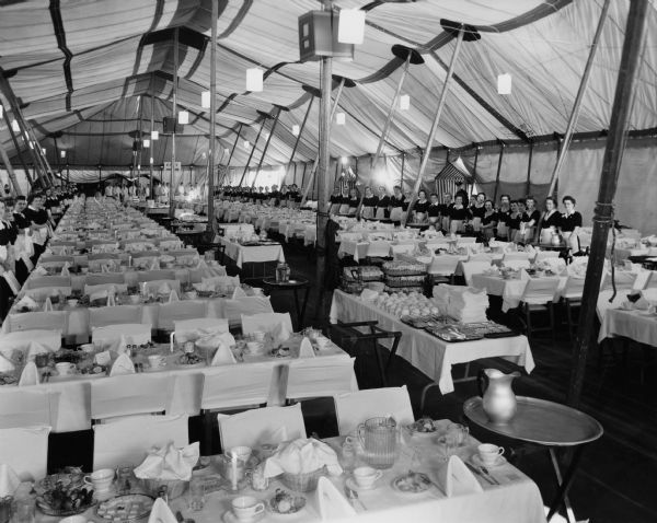 Waitresses and waiters lined up inside the Dining Tent, ready to serve a large gathering.
