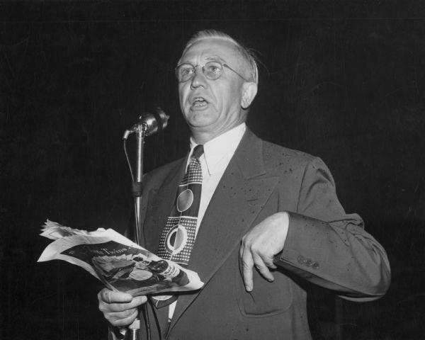 Governor Oscar Rennebohm speaking into a microphone on Governor's Day at the Wisconsin State Fair.