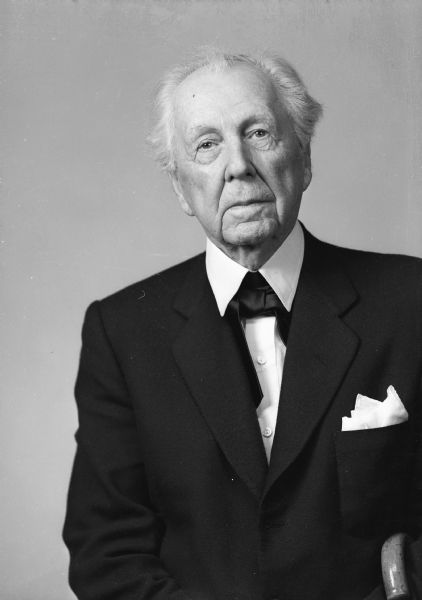 Unretouched passport photograph of Frank Lloyd Wright. He is holding a cane under his left arm.